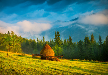 Wall Mural - amazing mountain landscape with fog and a haystack