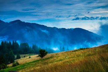 Wall Mural - amazing mountain landscape with fog and a haystack