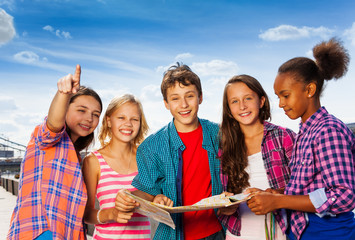 Smiling kids with map at city tours stand together