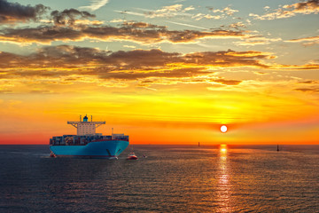 Wall Mural - Container ship on sea road during sunrise.