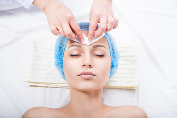 Skin care - woman cleaning face by beautician