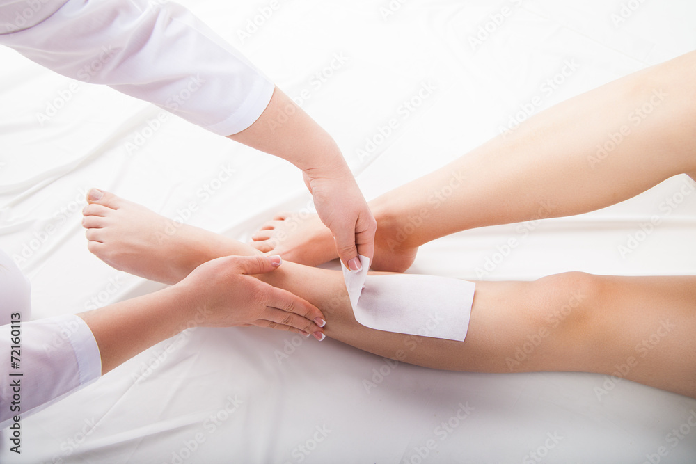 Beautician waxing  woman legs in spa salon - obrazy, fototapety, plakaty 