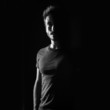 Dark shadow portrait of confident young man wearing shirt agains