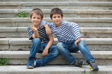 Two Brothers Portrait Having Fun Sit On Stairs Outdoors.