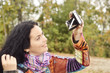 Brunette woman taking selfi pictures with an old photo camera outdoors