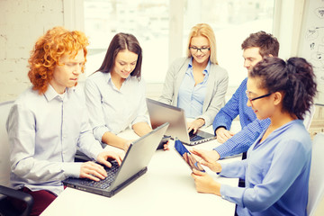 Canvas Print - smiling team with laptop and table pc computers