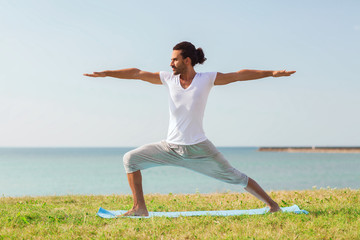 smiling man making yoga exercises outdoors