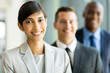 © michaeljung - indian female business leader with colleagues on background
