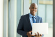 © michaeljung - african businessman holding laptop