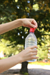 Wall Mural - Hand opening bottle with water on bright background