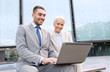 © Syda Productions - smiling businesspeople with laptop outdoors