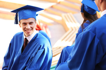 Poster - Graduate students wearing graduation hat and gown, outdoors