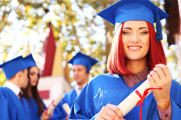 Wall Mural - Graduate students wearing graduation hat and gown, outdoors