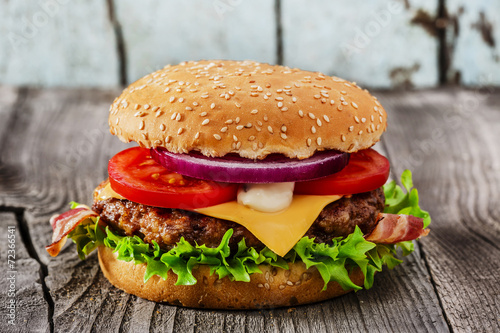 Fototapeta na wymiar hamburger with grilled meat cheese bacon on a wooden surface