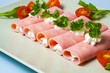 Rolled slices of ham filled with horseradish cream on plate