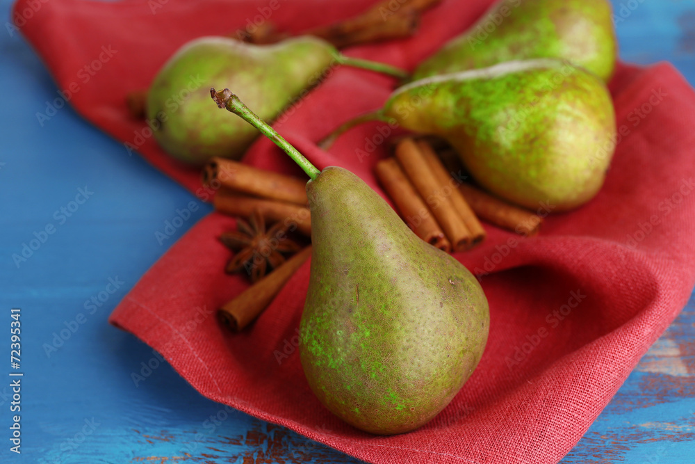 Ripe pears and cinnamon sticks  on color wooden background