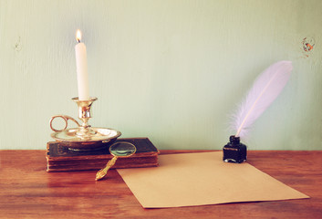 Wall Mural - low key image of white Feather, inkwell, burning Candle and anci