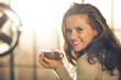 © Alliance - Portrait of happy young woman with cup of hot beverage