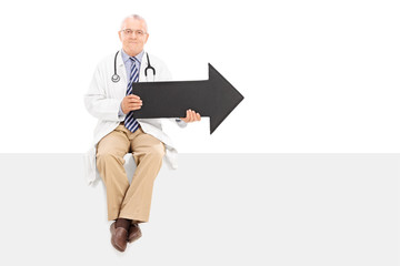 Sticker - Mature doctor holding an arrow and sitting on a panel