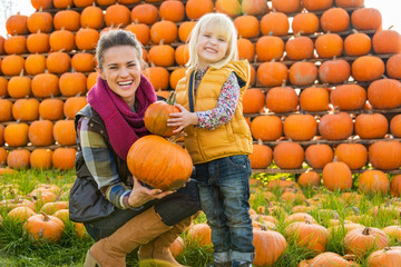 Wall Mural - Portrait of happy mother and child choosing pumpkins