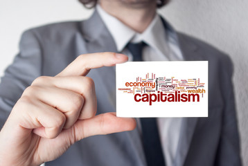 Sticker - Capitalism. Businessman in suit with a black tie showing or hold