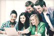 © Syda Productions - smiling students looking at laptop at school
