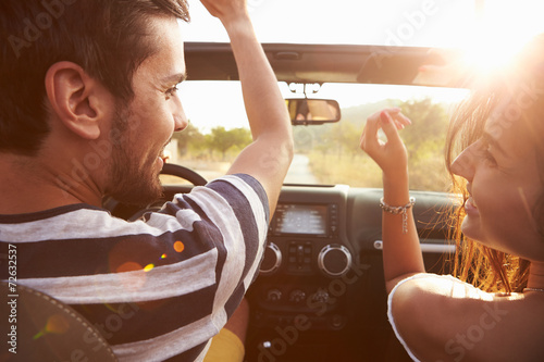 Fotografiet Young Couple Driving Along Country Road In Open Top Car
