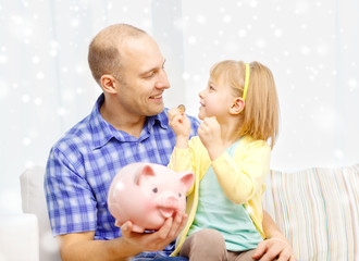 Wall Mural - happy father and daughter with big piggy bank