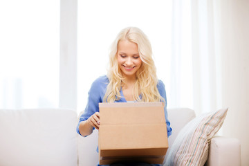 smiling young woman opening cardboard box