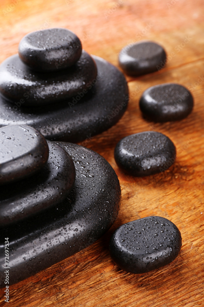 Spa stones with drops on wooden background