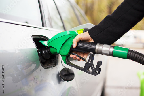 Fotomural Hand holding fuel pump and refilling car at petrol station