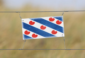 Border fence - Old plastic sign with a flag