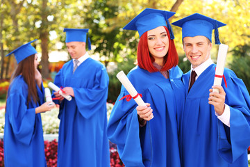 Wall Mural - Graduate students wearing graduation hat and gown, outdoors