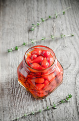 Wall Mural - Red peppers drops in glass jar on the wooden background