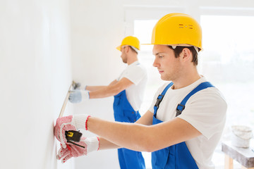 Canvas Print - group of builders with measuring tape indoors