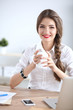 © lenets_tan - Young businesswoman sitting on the desk with cup in office
