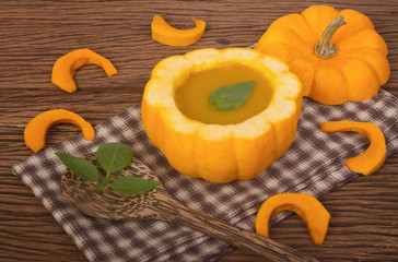 Pumpkin soup in a small pumpkin with herb leaf decoration in dis