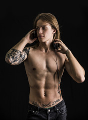 Muscular man shirtless listening to music on headphones