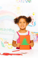 Girl holds carton card with Xmas tree and stands