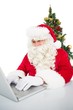 © WavebreakMediaMicro - Santa using his laptop near christmas tree