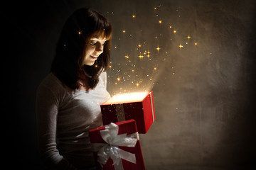 Beautiful  girl with magic holiday red gift on dark background