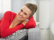 © Alliance - Portrait of happy young woman sitting on sofa
