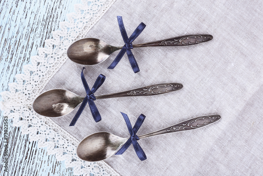 Spoons on lace napkin on wooden background