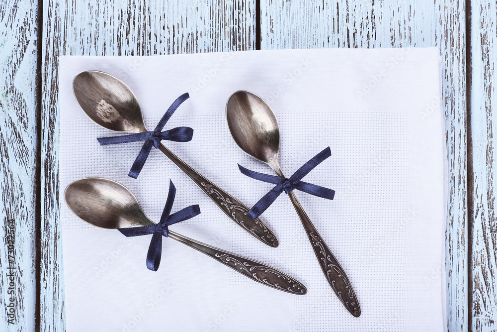 Metal spoons on white napkin on wooden background