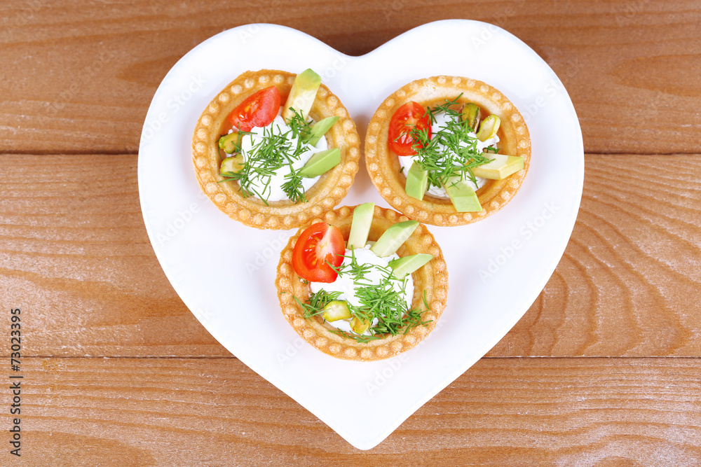 Tartlets with greens and vegetables with sauce on plate on