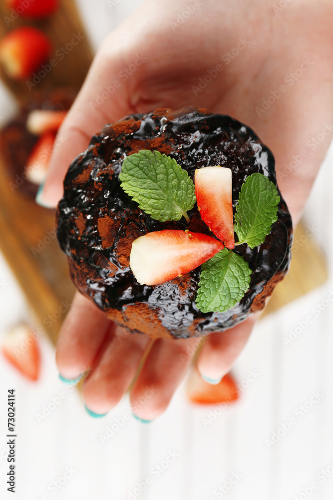 Yummy chocolate cupcake in hand, close-up