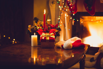 Toned photo of burning candles, fireplace and giftbox at christm