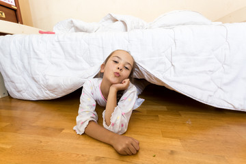 young little girl lying on floor at bedroom under bed