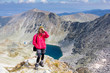 © subbotsky - Woman standing mountain edge above lake.