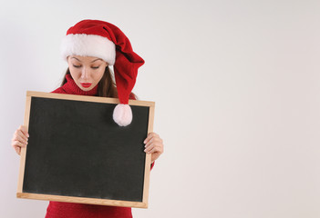 funny amazed young woman with blackboard in santa hat on white b